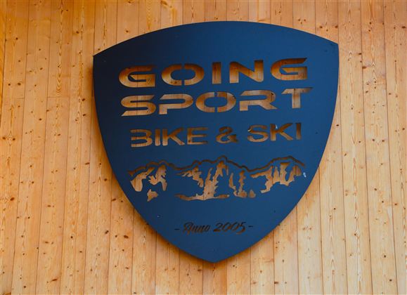 Ein schwarzes Schild mit der Aufschrift "GOING SPORT BIKE & SKI". Es zeigt eine Bergsilhouette und das Gründungsjahr 2005.