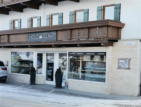 Een gezellige winkel met een uitnodigende etalage. Boven bevindt zich een houten balkon met klassieke ramen.