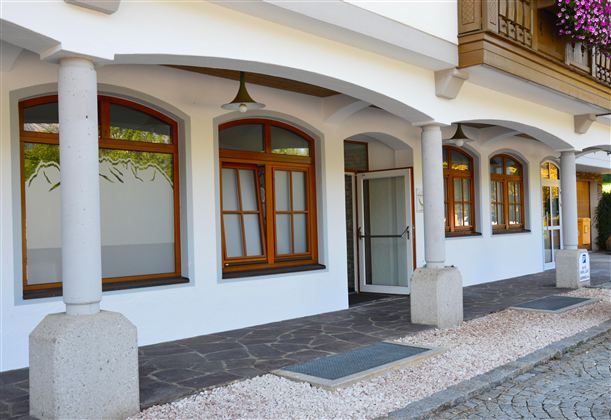 A house with an elegant entrance and several windows. The facade is painted light, and the ground is designed with pebbles.
