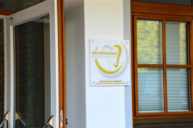 An entrance with modern signage for a dental clinic. The glass front and wooden framed window create an inviting atmosphere.