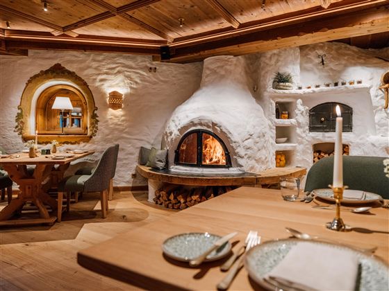 Een gezellig restaurant met een open haard en rustieke houten decoratie. De tafels zijn elegant gedekt en creëren een uitnodigende sfeer.