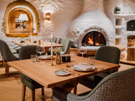 Een gezellig restaurant met een houtoven en stijlvolle meubels. De tafel is elegant gedekt en creëert een uitnodigende sfeer.