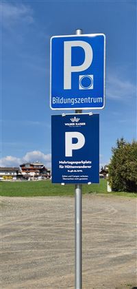 Ein Parkplatzschild für ein Bildungszentrum. Darunter befindet sich ein zusätzliches Schild für Halteplätze.