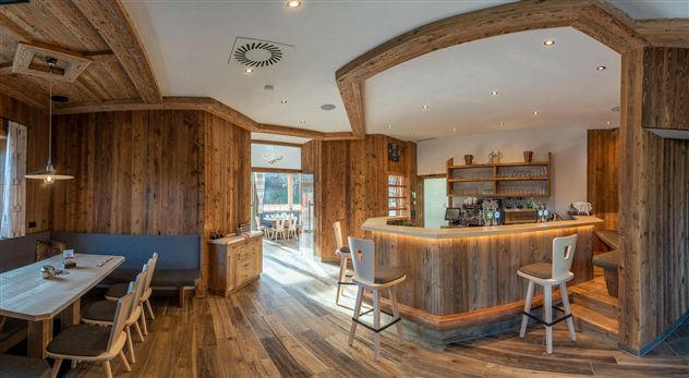 Een modern restaurant met houten elementen en een gezellige sfeer. De bar is goed uitgerust, en er is een uitzicht op buiten.