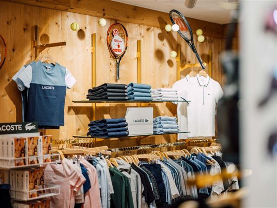 Een moderne kledingwinkel met houten planken en goed gesorteerde accessoires. Mannequin in sportieve kleding staat in het midden van de ruimte.
