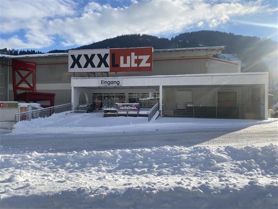 Een meubelhuis met de naam "XXX Lutz" in de winter. De ingang is bedekt met sneeuw en de omgeving ziet er winterachtig uit.