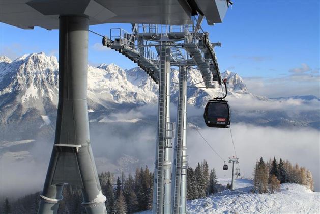 Een kabelbaan rijdt over met sneeuw bedekte bergen. Het uitzicht toont een pittoresk winterlandschap met mist in de vallei.