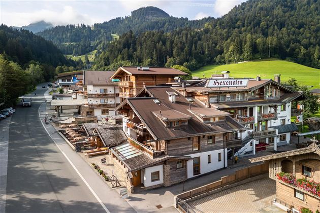A picturesque mountain landscape with traditional wooden buildings. The surroundings are green and tranquil, with a road that runs through the village.