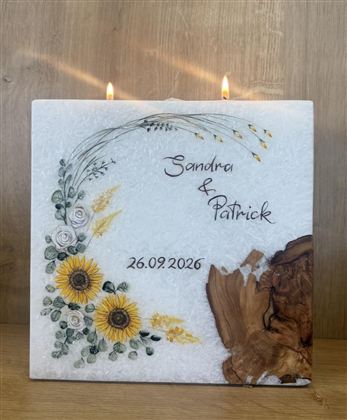 Eine dekorative Tafel mit der Aufschrift "Sandra & Patrick" und dem Datum "26.09.2026". Umgeben von Blumenmotiven und einer Holzstruktur, die eine warme Atmosphäre schafft.