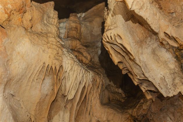 An impressive cave landscape with fascinating stalactites and stalagmites. The rocks display interesting formations and textures.