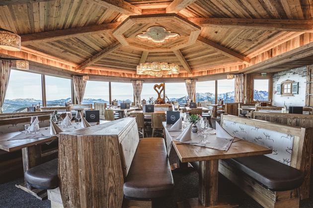 Een gezellig restaurant met houten decor en grote ramen. Het uitzicht op de bergen zorgt voor een uitnodigende sfeer.