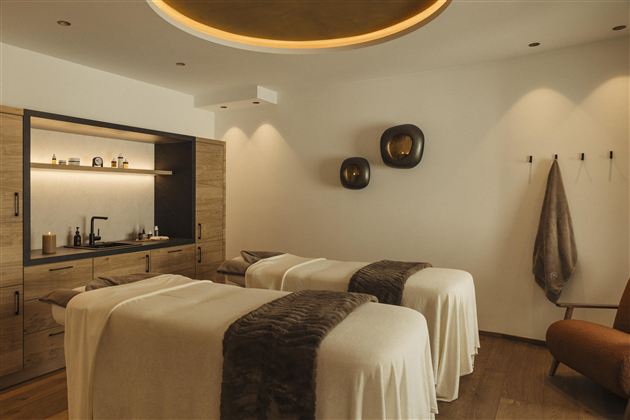 An elegant spa with two treatment beds and warm colors. The decor is modern and inviting.
