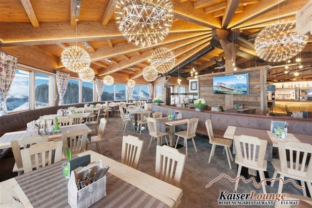 Eine gemütliche Restaurantlounge mit Holzinterieur und großen Fenstern. Kristallleuchter sorgen für eine besondere Atmosphäre.