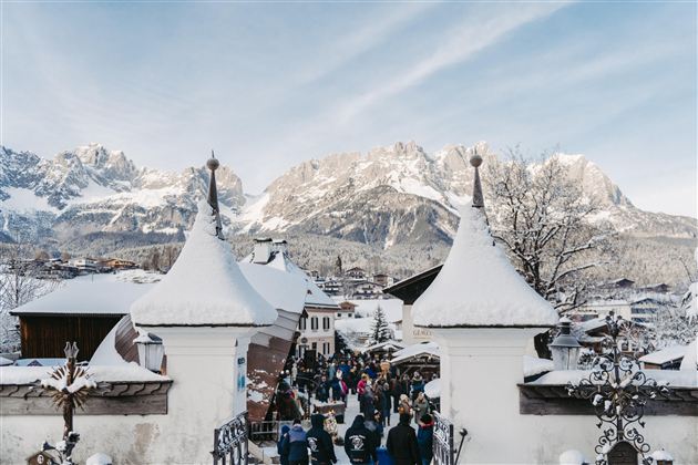 Een besneeuwd landschap met majestueuze bergen op de achtergrond. Bezoekers verkennen de pittoreske stad onder een heldere lucht.