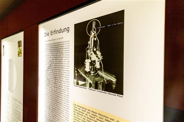 Ein Ausstellungsstück zeigt eine historische Erfindung mit einer technischen Vorrichtung. Daneben befindet sich ein Text, der die Erfindung beschreibt.