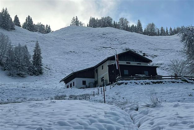 Een gezellig huis in een besneeuwd landschap. De heuvel op de achtergrond is bedekt met verse sneeuw.