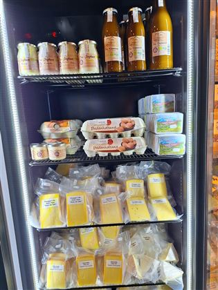Een koelkast vol levensmiddelen-specialiteiten. Hij bevat flessen, eieren en verschillende soorten kaas.