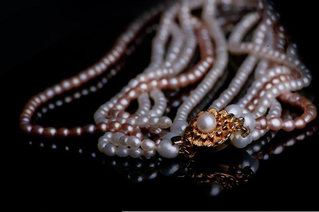 An elegant pearl necklace with a golden clasp. The pearls are shiny and give a timeless impression.