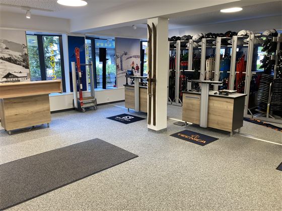 Ein modernes Sportgeschäft mit Skiausrüstung und Zubehör. Die Einrichtung ist hell und einladend, mit Platz für Beratung und Verkauf.