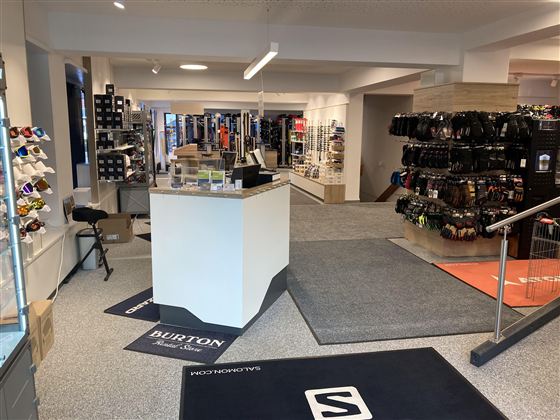 Ein moderner Sportgeschäft mit verschiedenen Produkten für Outdoor-Aktivitäten. Die Regale sind gefüllt mit Ausrüstung und Zubehör.