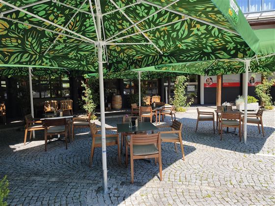 Een modern restaurant met houten details en comfortabele rode stoelen. De verlichting is aangenaam en creëert een uitnodigende sfeer.