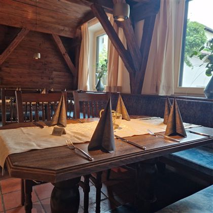 A cozy restaurant with wooden furniture and an open fireplace. The warm colors and the loving decoration create an inviting atmosphere.