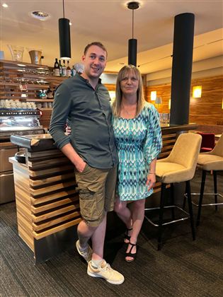 A man and a woman are standing in a modern restaurant. The decor is bright and inviting.