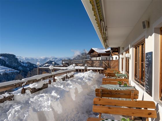 Een mooie berglandschap met sneeuwbedekte terrassen en een blauwe lucht. De houten stoelen nodigen uit om te ontspannen.