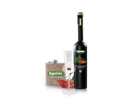 Een fles likeur met rode bessen, een glas en een decoratieve doos. Het product komt van het merk Aggstein.