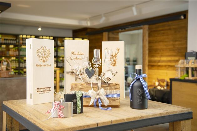 Een decoratieve tafel met verschillende geschenkverpakkingen en een fles. De verpakkingen zijn van hout en bevatten mooie ontwerpen.