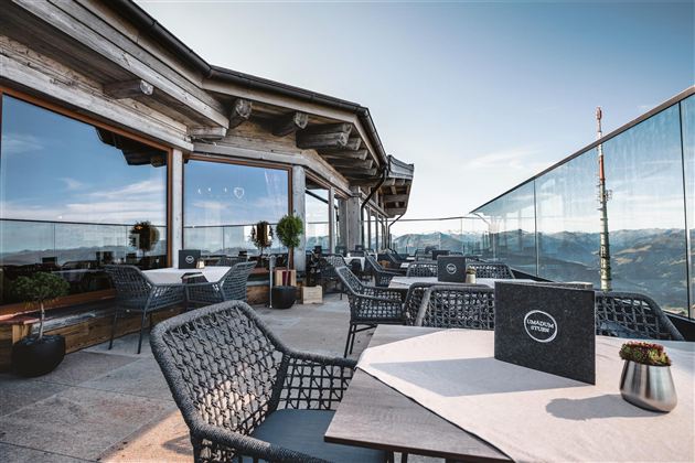 Een modern terras met uitzicht op de bergen. Er zijn gezellige zitplaatsen en een heldere lucht.