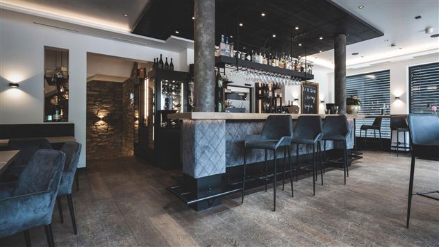 Eine elegante Bar mit modernen Möbeln und gedämpfter Beleuchtung. Der Raum ist stilvoll eingerichtet und lädt zum Verweilen ein.