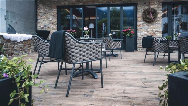 Eine gemütliche Terrasse mit modernen Stühlen und Tischen. Blumen in Töpfen verleihen dem Raum einen einladenden Charakter.