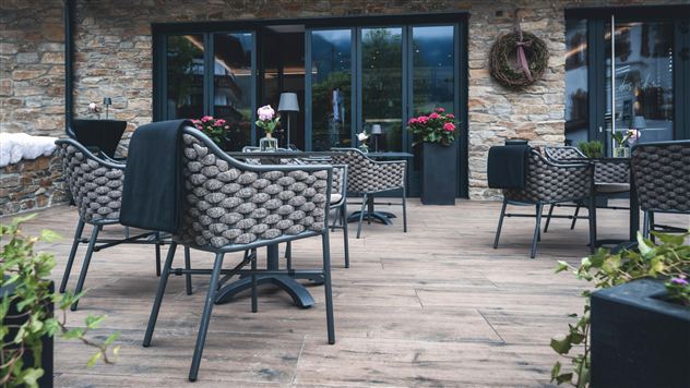 Ein stilvolles Restaurant mit einem Holzdeck und modernen Möbeln. Benötigte Pflanzen und Blumen sorgen für eine einladende Atmosphäre.
