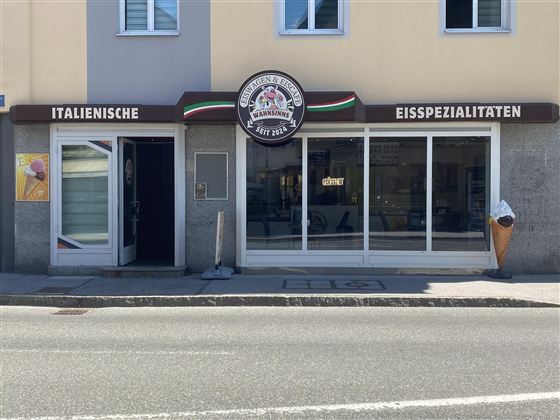 An ice cream parlor with a modern entrance and large windows. The signage displays Italian ice cream specialties.