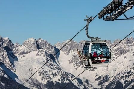 A cable car travels over snow-covered mountains. The clear sky and the majestic peaks create an impressive winter landscape.