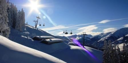 Een schilderachtig winterlandschap met sneeuwbedekte bergen en een heldere blauwe lucht. Skiliften rijden over de besneeuwde piste.