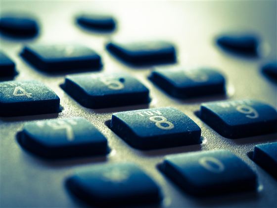A close-up of a telephone keypad with black keys and white numbers. The keys are slightly staggered, and the background is blurred.