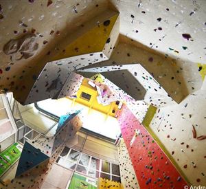 Eine Kletterhalle mit bunten Kletterwänden und vielen Griffen. Die Decke ist hoch und bietet verschiedene Routen für Kletterer.