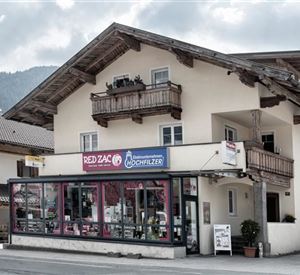 A traditional building in the Alps with a commercial area on the ground floor. The weather is cloudy, beautiful mountain scenery in the background.