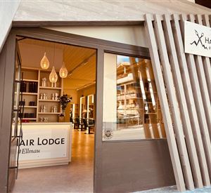 Ein moderner Friseursalon mit dem Namen "Hair Lodge" in Ellmau. Die Eingangstür ist einladend und zeigt einen hellen, minimalistischen Innenraum.