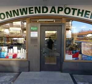 Eine Apotheke namens Sonnwend mit einem einladenden Eingang. Im Fenster sind verschiedene Produkte sichtbar.