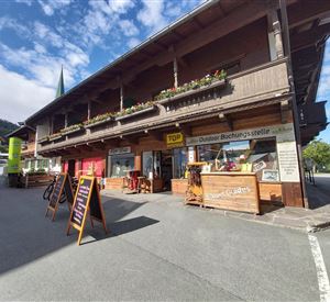 A traditional wooden building with colorful flowers on the balcony. Outside, there are signs for outdoor activities and bookings.