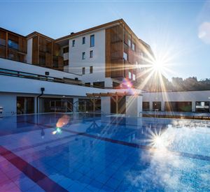 Een modern hotel met een glinsterend zwembad. De zoninval zorgt voor een uitnodigende sfeer.