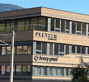 Ein modernes Gebäude mit Holzfassade. Die Unternehmensnamen "PLETZER" und "brewa grund" sind deutlich sichtbar.