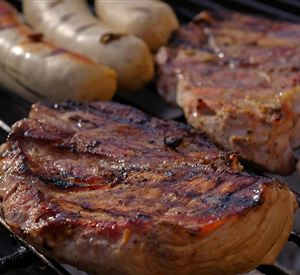 Gegrild vlees en worstjes op de grill. Het oppervlak is mooi bruin en krokant.