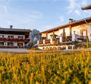 Ein charmantes Bauernhaus mit schöner Blumenbepflanzung liegt in einer malerischen Landschaft. Der sanfte Morgenlichtschein schafft eine einladende Atmosphäre.
