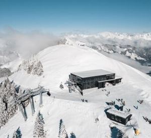 A snow-covered mountain landscape with a modern mountain station and lifts. Many people enjoy winter activities in the beautiful surroundings.