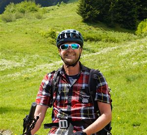 A cheerful cyclist on a green path. In the background, trees and a picturesque landscape can be seen.