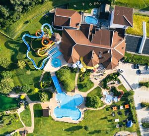 Een grote recreatievoorziening met meerdere zwembaden en glijbanen. De accommodatie is omgeven door groene weilanden en bomen.